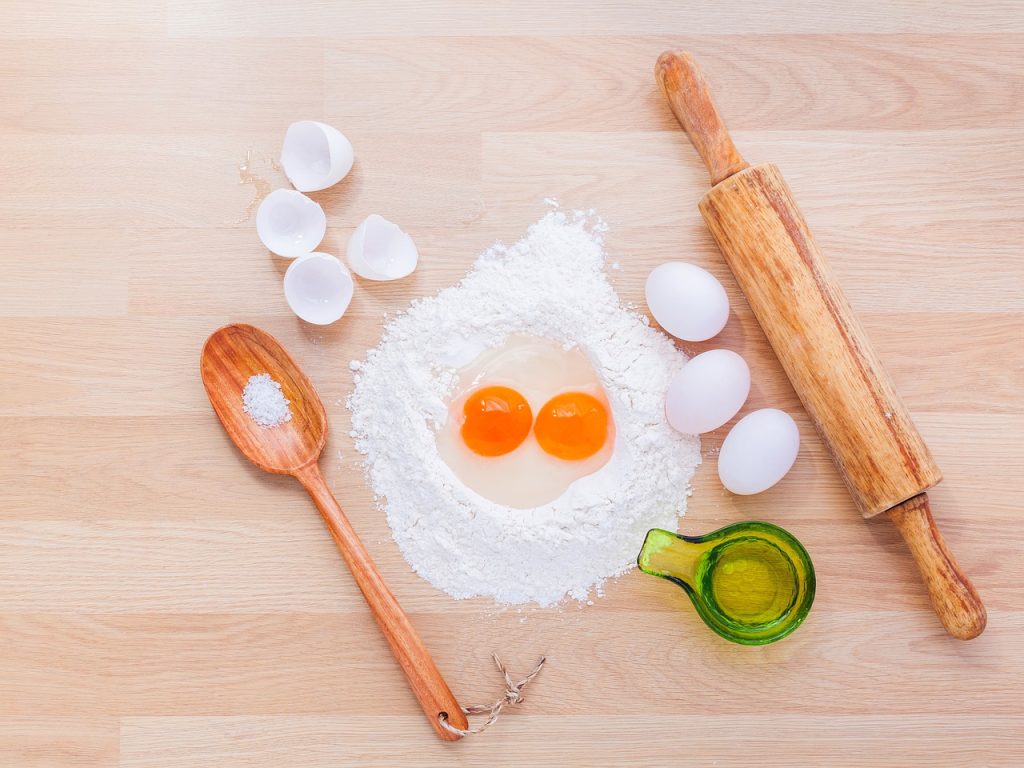 baking supplies  - wooden utensils with flour eggs and measuring cups.